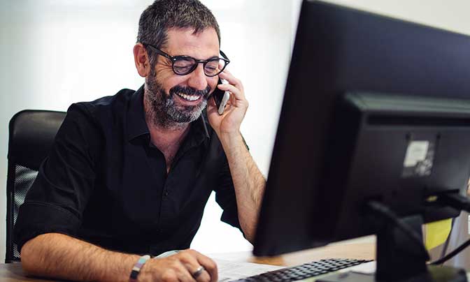 Carlos está hablando por su móvil frente a un monitor